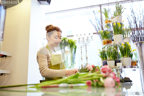 Image of smiling florist woman making bunch at flower shop