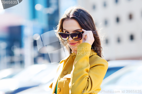Image of smiling young woman with sunglasses in city