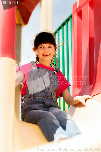 Image of happy little girl on slide at children playground