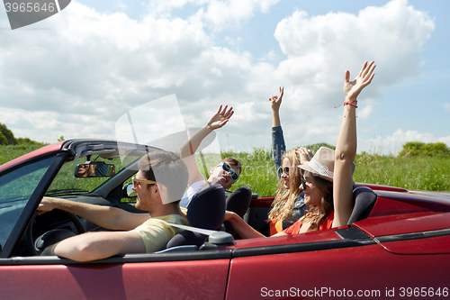 Image of happy friends driving in cabriolet car at country