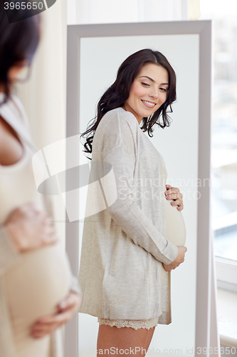 Image of happy pregnant woman looking to mirror at home