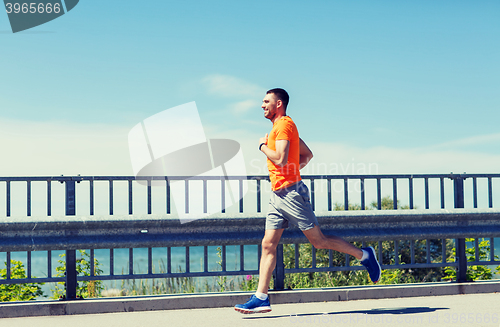 Image of smiling young man running at summer seaside