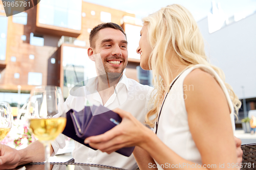 Image of happy couple with wallet paying bill at restaurant