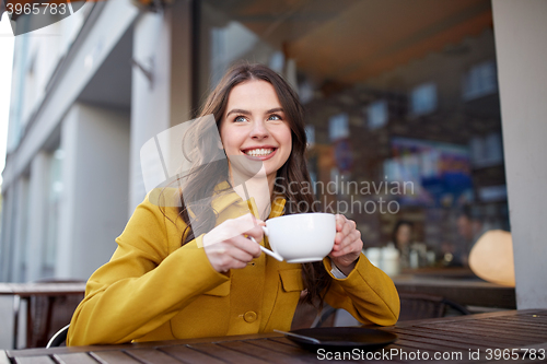 Image of happy woman drinking cocoa at city street cafe