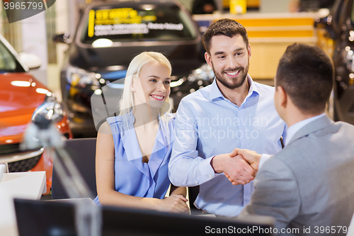 Image of happy couple with car dealer in auto show or salon