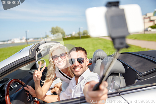 Image of happy couple in car taking selfie with smartphone