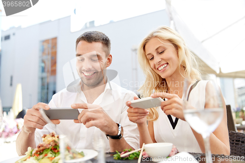 Image of happy couple with smatphone photographing food