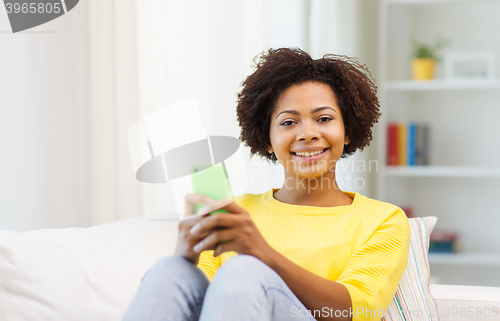 Image of happy african woman with smartphone at home