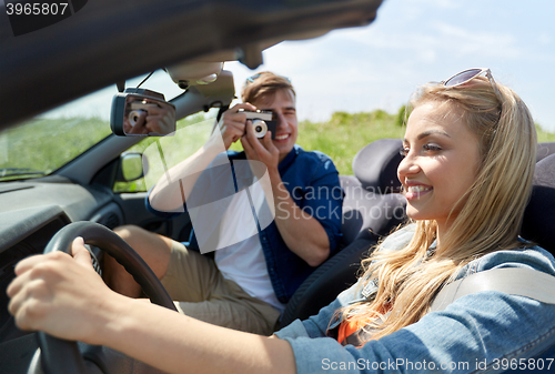 Image of man photographing woman driving car by film camera