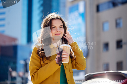 Image of happy young woman drinking coffee on city street