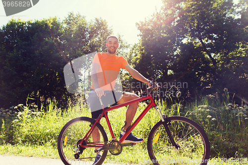 Image of happy young man riding bicycle outdoors