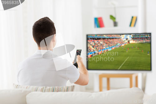 Image of man watching football or soccer game on tv at home