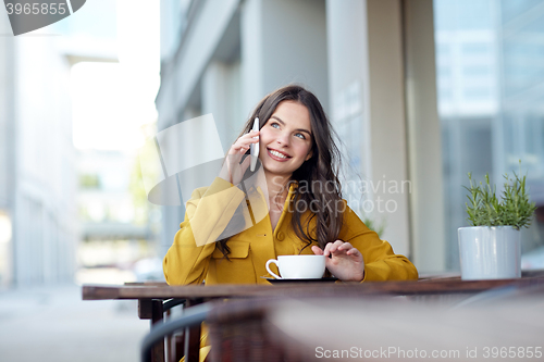 Image of happy woman calling on smartphone at city cafe