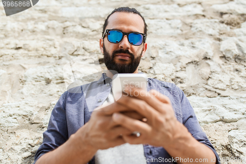 Image of man texting message on smartphone at stone wall