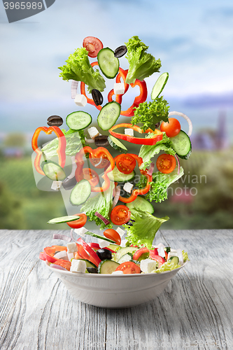Image of Fresh mixed vegetables falling into a bowl of salad