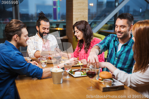 Image of friends eating and tasting food at restaurant