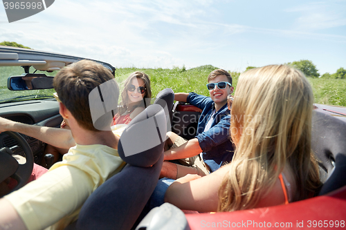 Image of happy friends driving in cabriolet car and talking