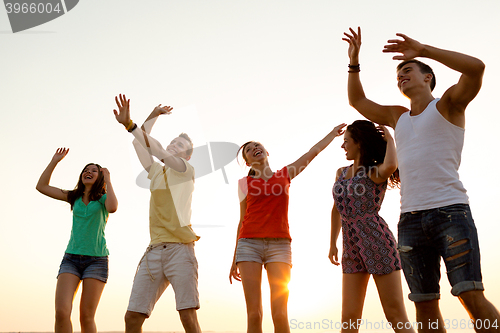 Image of smiling friends dancing on summer beach