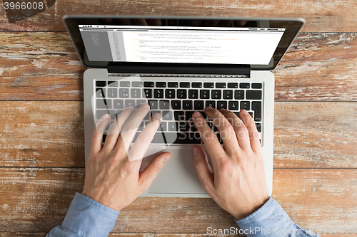 Image of close up of male hands with laptop typing