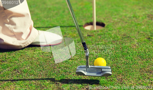 Image of close up of man with club and ball playing golf