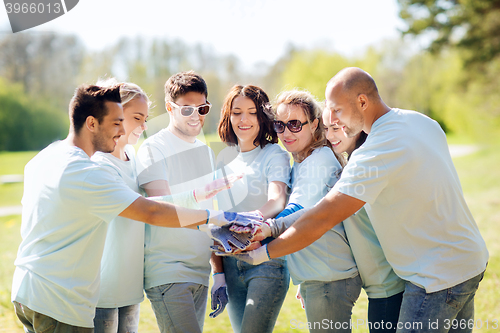 Image of group of volunteers putting hands on top in park