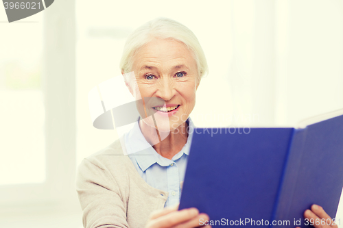 Image of happy smiling senior woman reading book at home