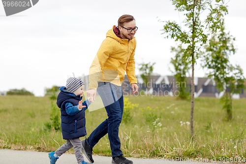 Image of happy father and little son walking outdoors