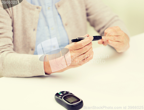 Image of senior woman with glucometer checking blood sugar