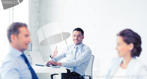 Image of happy businessman showing thumbs up in office