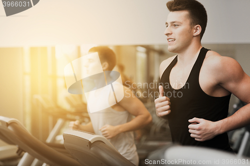 Image of smiling men exercising on treadmill in gym