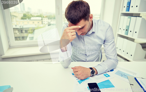 Image of stressed businessman with papers in office