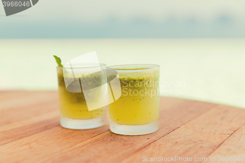 Image of glasses of fresh juice or cocktail on beach