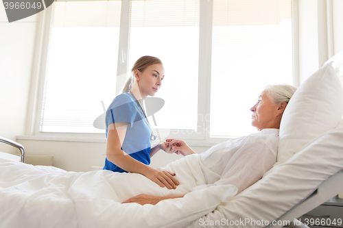 Image of doctor or nurse visiting senior woman at hospital