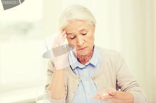 Image of senior woman with water and medicine at home