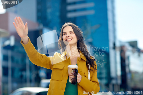 Image of happy young woman drinking coffee on city street