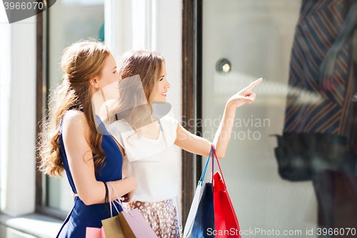 Image of happy women with shopping bags at shop window