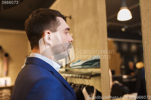 Image of man in jacket looking to mirror at clothing store