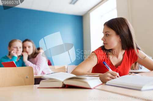 Image of students gossiping behind classmate back at school