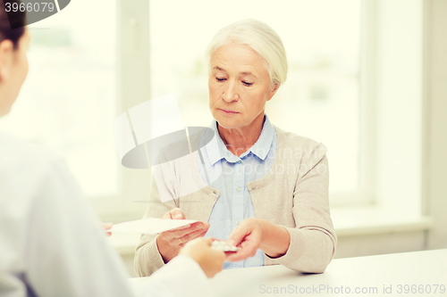 Image of doctor giving prescription and drug to woman 