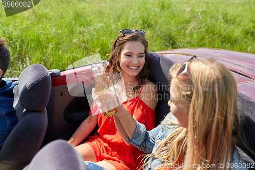 Image of happy friends driving in cabriolet car with beer