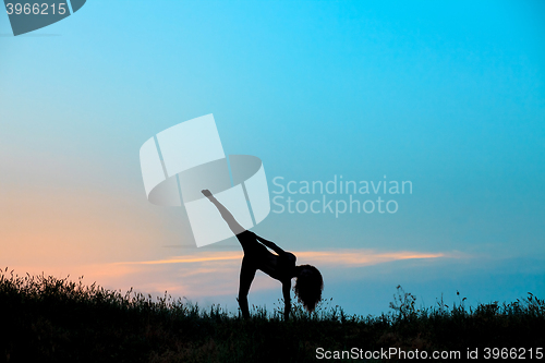 Image of The silhouette of young woman is practicing yoga