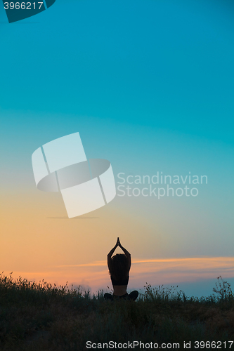 Image of The silhouette of young woman is practicing yoga