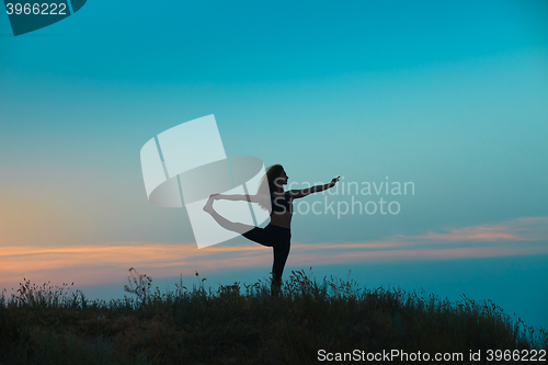 Image of The silhouette of young woman is practicing yoga