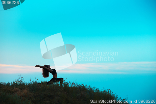 Image of The silhouette of young woman is practicing yoga