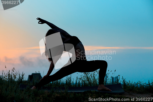 Image of The silhouette of young woman is practicing yoga