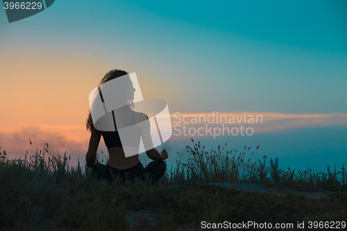 Image of The silhouette of young woman is practicing yoga