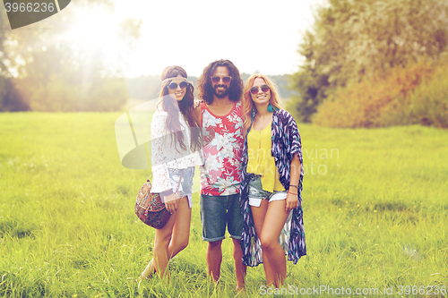 Image of smiling young hippie friends on green field