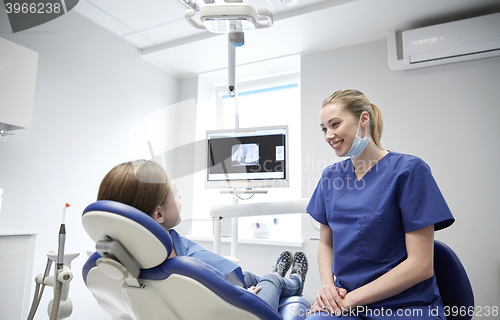Image of happy female dentist with patient girl at clinic