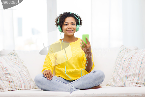 Image of happy african woman with smartphone and headphones