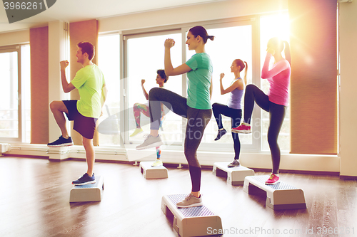 Image of group of people working out with steppers in gym